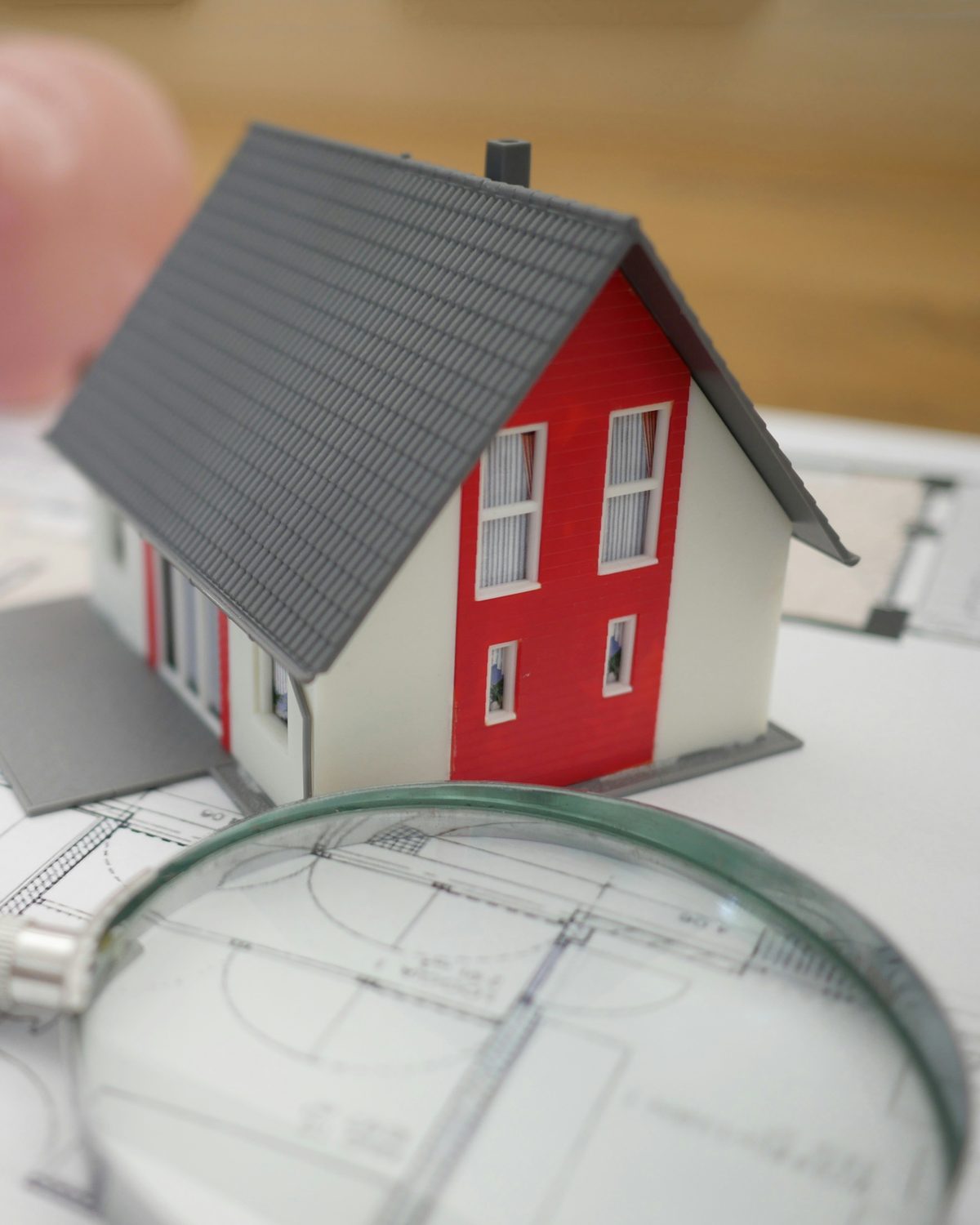 Hausmodell auf Bauplan mit Lupe